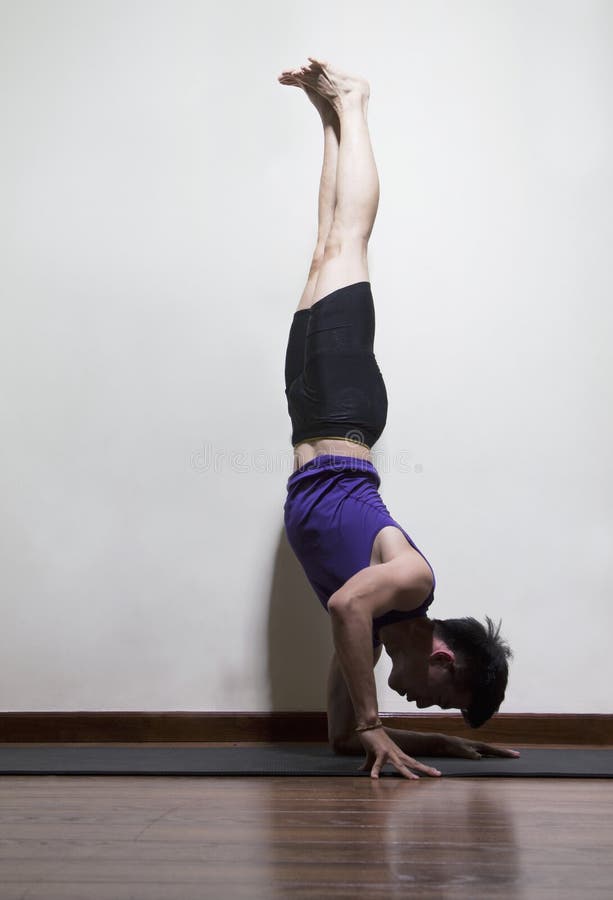Upside Down Man Doing Yoga in a Yoga Studio, Side View Stock Image