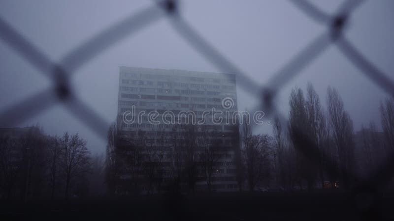 Urban city backgrounds. Multi-storey building in the morning, in the fog. Apartment building behind bars. Ghetto