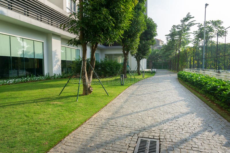 Urban walking road among green trees inside modern apartment building area in big city