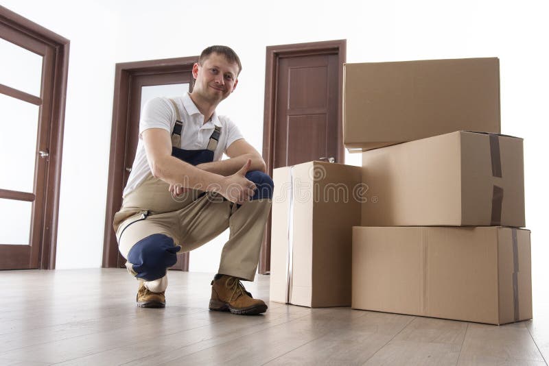 Urheber mit Pappschachteln in der Wohnung Verlegungsdienstleistungen Lader hält Daumen hoch lizenzfreies stockfoto Urheber mit Pappschachteln in der Wohnung Verlegungsdienstleistungen Lader hält Daumen hoch lizenzfreies stockfoto