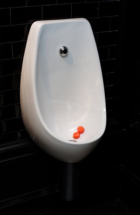 Urinal Bowl with Antiseptic Tablets in Dark Restroom Stock Image