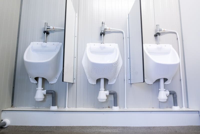 Two Urinals Next To Each Other with a Seperator in between Stock Image