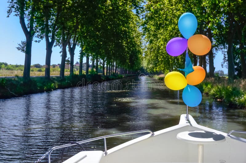 Vacation boat with balloons in Canal du Midi, family travel river cruise by barge penichette, holidays in Southern France. Vacation boat with balloons in Canal du Midi, family travel river cruise by barge penichette, holidays in Southern France
