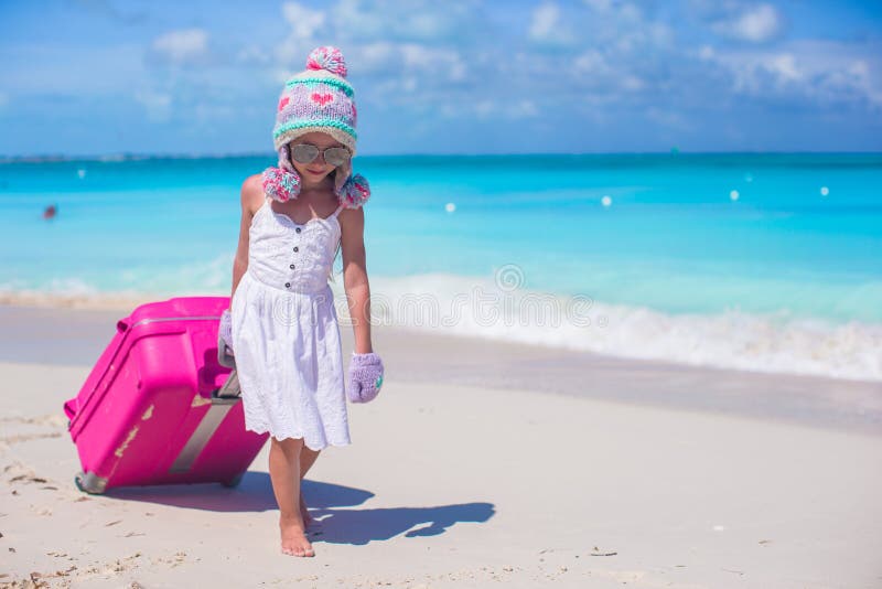 Urocza dziewczyna chodzi z bagażem na plaży w ciepłym zima kapeluszu, mitynkach i fotografia royalty free Urocza dziewczyna chodzi z bagażem na plaży w ciepłym zima kapeluszu, mitynkach i fotografia royalty free