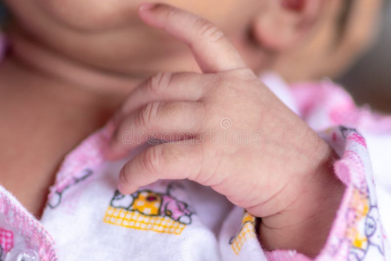 Adorable cute baby girls hand and fingers close up macro photography, her veins also visible as she`s only three weeks old infant. Dressed in beautiful pink clothes. Adorable cute baby girls hand and fingers close up macro photography, her veins also visible as she`s only three weeks old infant. Dressed in beautiful pink clothes