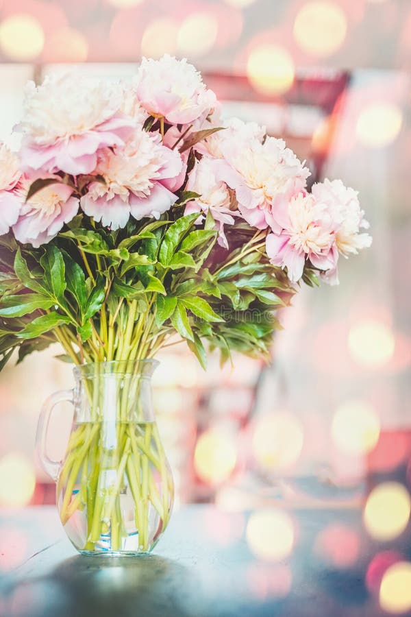 Urocze różowe peonie kwitną wiązkę w wazie przy światła słonecznego bokeh zdjęcie stock