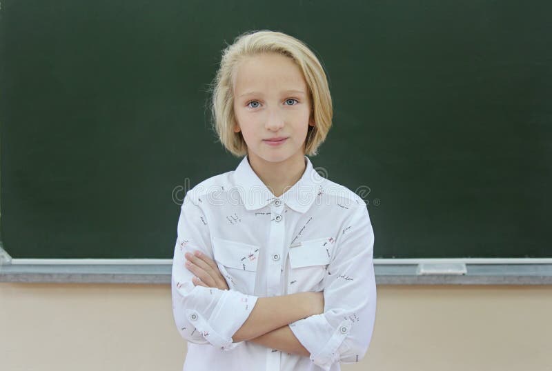 Uroczy blondynki uczennicy 9-11 lat w sala lekcyjnej blisko chalkboard tylna szkoły obrazy stock Uroczy blondynki uczennicy 9-11 lat w sala lekcyjnej blisko chalkboard tylna szkoły obrazy stock