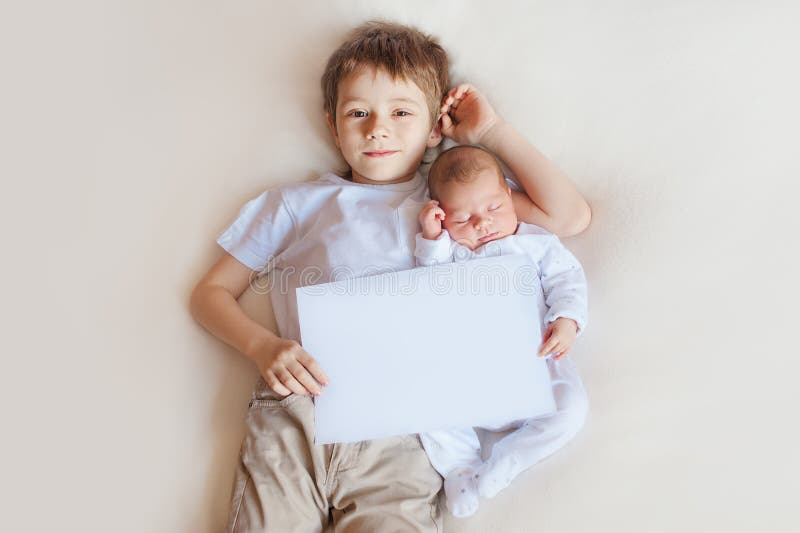 Little brother hugging her newborn baby. Toddler kid meeting new sibling. Cute boy and new born baby girl relax in a white bedroom. Family with children at home. Love, trust and tenderness. Little brother hugging her newborn baby. Toddler kid meeting new sibling. Cute boy and new born baby girl relax in a white bedroom. Family with children at home. Love, trust and tenderness