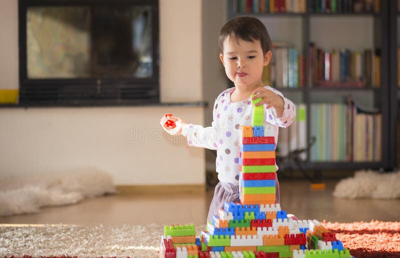 Uroczy roześmiany małe dziecko, brunetki preschool pełnoletni bawić się z kolorowymi blokami dziewczyna siedzi na podłoga obraz stock