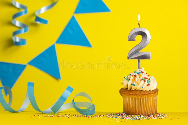 Lighted birthday candle number 2 - Yellow background with blue pennants. Lighted birthday candle number 2 - Yellow background with blue pennants