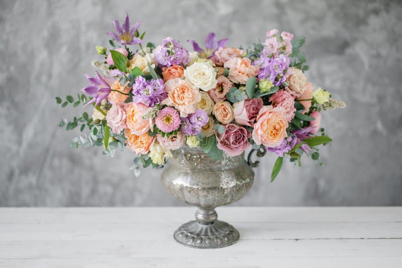 Ursnygg bukett av olika blommor blom- ordning i tappningmetallvas Table inställningen lila- och persikafärg royaltyfria foton