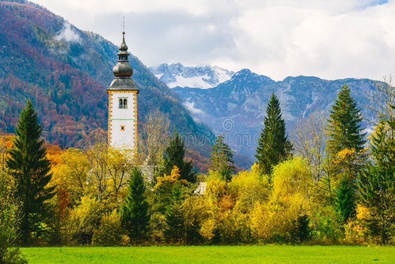 Ursnygg sikt av den färgrika höstliga platsen av den berömda kyrkan av St John det baptistiskt på Bohinj sjön royaltyfri bild Ursnygg sikt av den färgrika höstliga platsen av den berömda kyrkan av St John det baptistiskt på Bohinj sjön royaltyfri bild