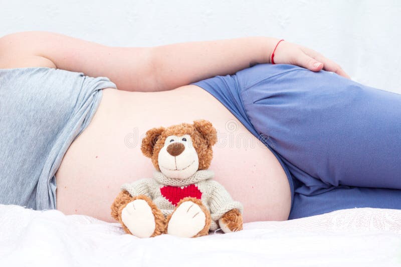 Urso de peluche ao lado da barriga de uma mulher gravida fotografia de stock Urso de peluche ao lado da barriga de uma mulher gravida fotografia de stock