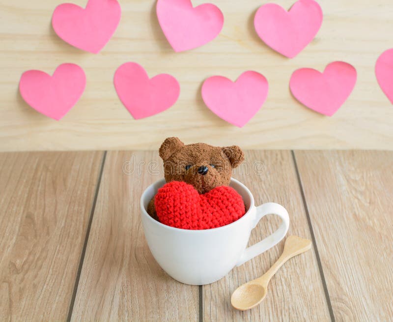 Urso de peluche na xícara de café com forma vermelha do coração na tabela de madeira imagens de stock Urso de peluche na xícara de café com forma vermelha do coração na tabela de madeira imagens de stock