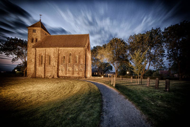 Dramatic view of the Ursus church in Termunten. the Netherlands in the evening light. The Ursus church is an early Gothic church that dates to the 13th century.