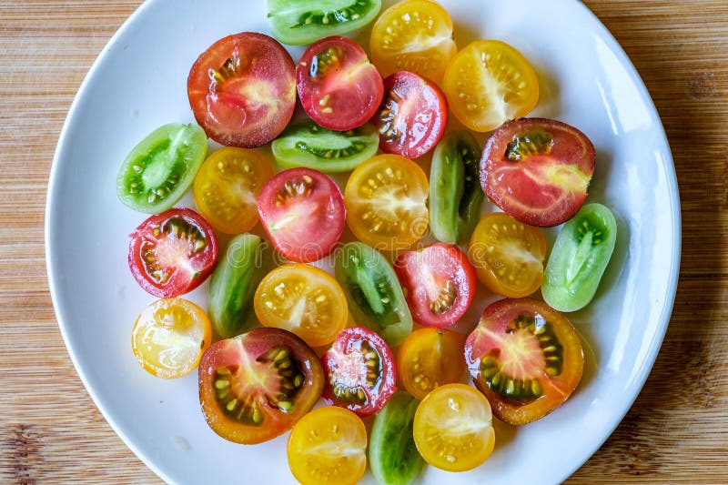 Urval av små, färglösa, skivade, rå sommartomater arkivbild