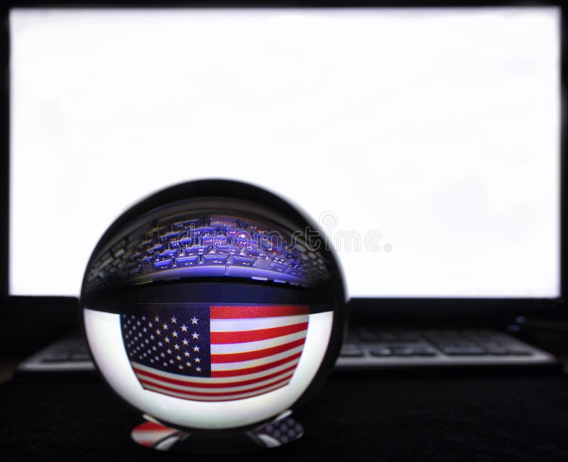 US flag and keyboard in reflection on a crystal ball against a white monitor in blur