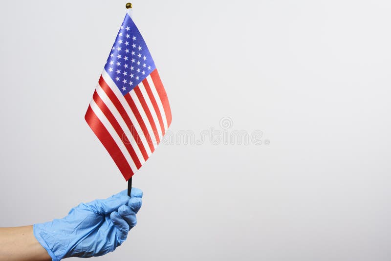The US flag in a person`s hand with a medical glove