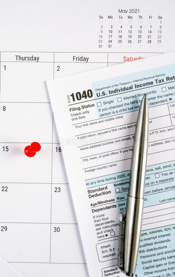 Us individual income tax return 1040 form for 2020 with red pin on april 15th 2021 calendar. stock images