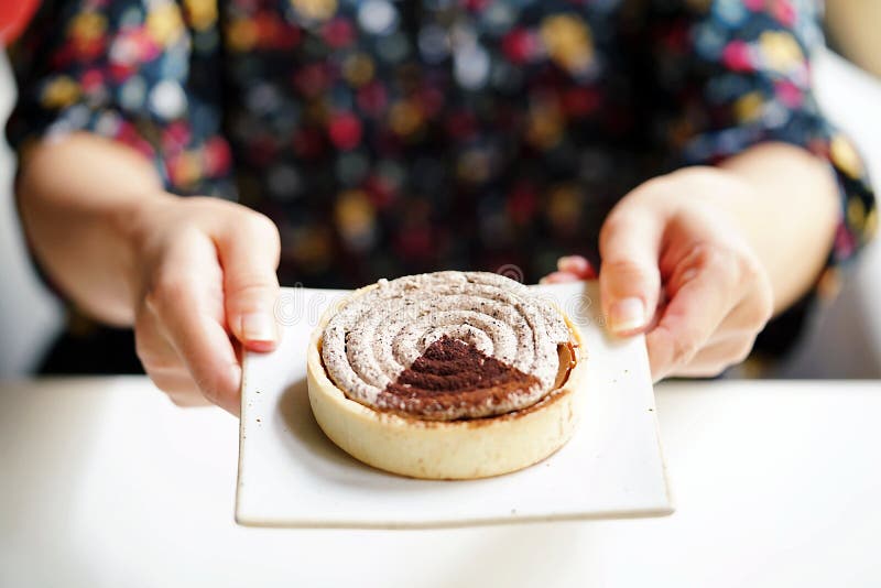 Usando la mano del perno que sostiene una placa blanca, postre delicioso, postre italiano, tarta redondeada del tiramisu colocada fotografía de archivo libre de regalías Usando la mano del perno que sostiene una placa blanca, postre delicioso, postre italiano, tarta redondeada del tiramisu colocada fotografía de archivo libre de regalías