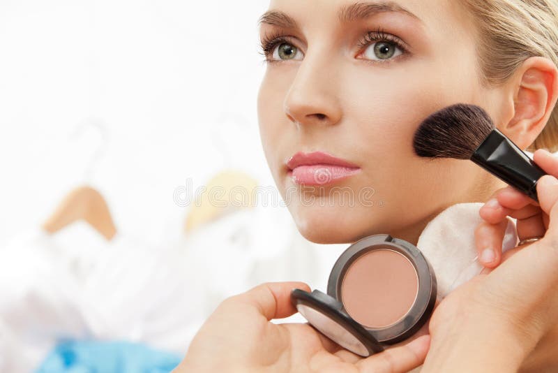 Using blush brush to apply blush on cheeks - professional makeup artist working. Using blush brush to apply blush on cheeks - professional makeup artist working