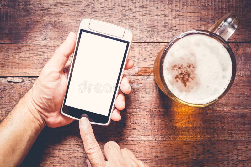 Usando smartphone por otra parte de la cerveza en el pub imagen de archivo libre de regalías Usando smartphone por otra parte de la cerveza en el pub imagen de archivo libre de regalías
