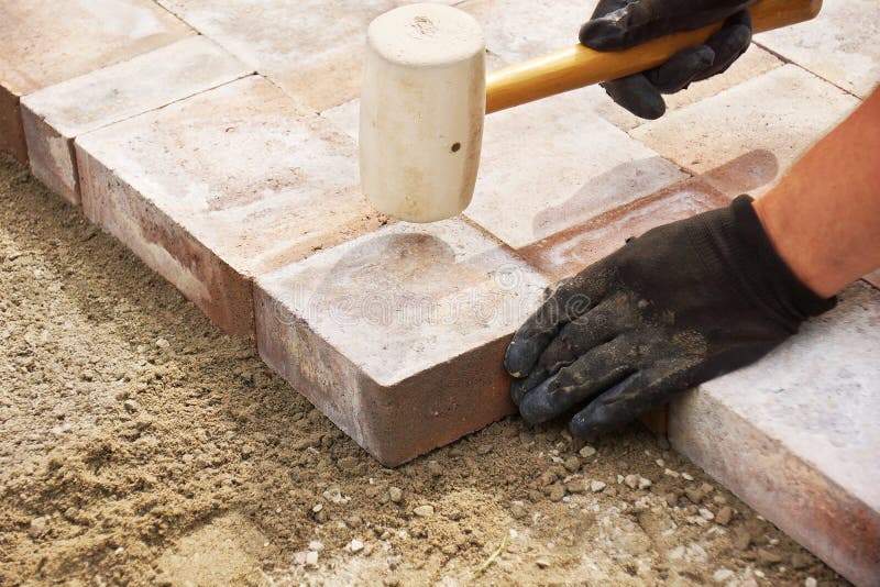 Installing paver bricks on patio, mallet to level the stones. Installing paver bricks on patio, mallet to level the stones