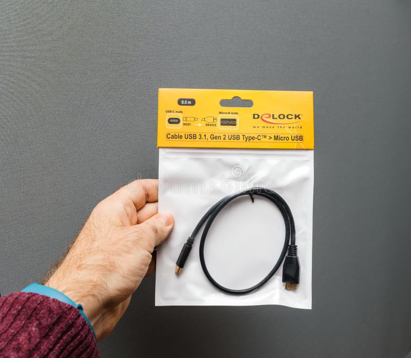 USB-C au câble micro d'USB pour l'ordinateur portable d'Apple. PARIS, FRANCE - 23 JANVIER 2018 : Homme tenant la GEN 2 d'USB 3 1 type-c d'USB à l'adaptateur micro d'USB sur le fond gris
