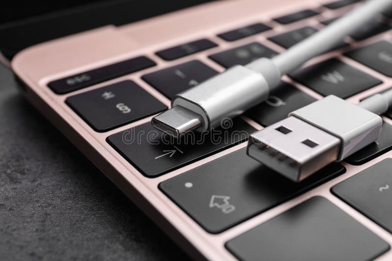 USB Cable with Type C Connector and Laptop on Dark Table, Closeup Stock