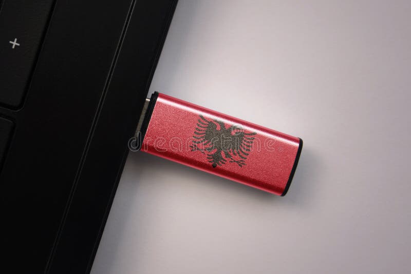 Usb flash drive in notebook computer with the national flag of albania on gray background. concept