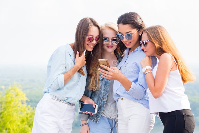 A group of beautiful girls look at the phone girlfriend and laugh. 