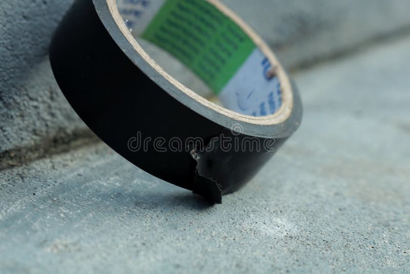 Used Black Duct Tape that Has Been Used on a Gray Background Stock