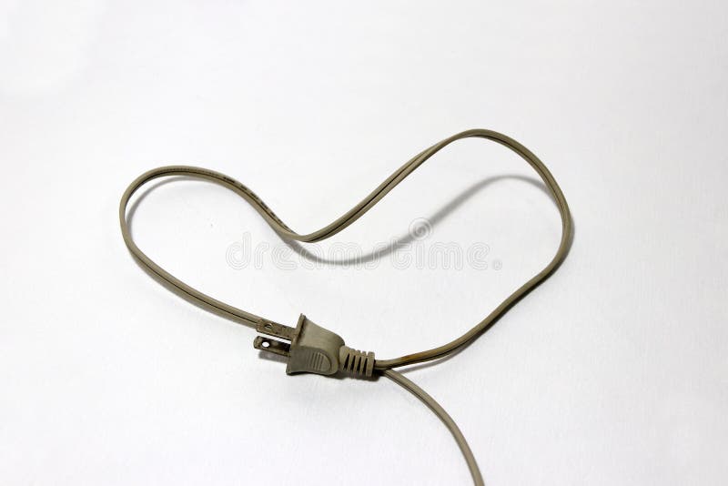 Used cream color of plug with cable put like a heart on the white floor, love concept of electrician. royalty free stock photography Used cream color of plug with cable put like a heart on the white floor, love concept of electrician. royalty free stock photography