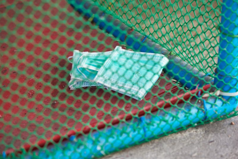 Used face masks in specific trash with net on the ground