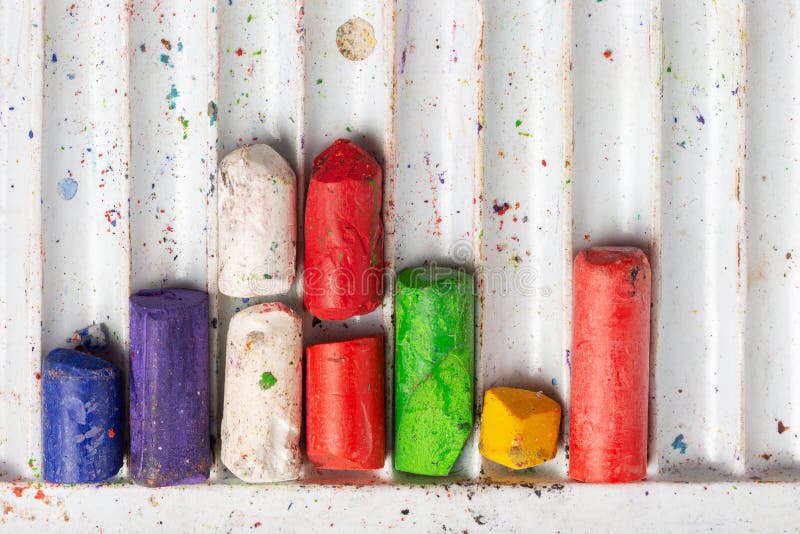 A close up photograph of a box of colorful used chalk pastels