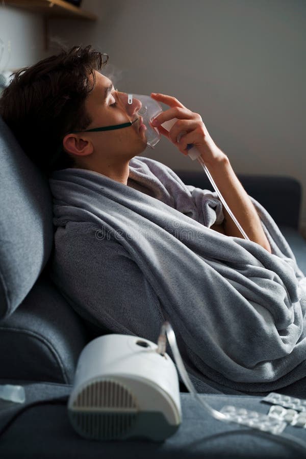 Using compressor nebulizer for disease treatment at home. Man inhaling through oxygen mask for cough treatment. royalty free stock image