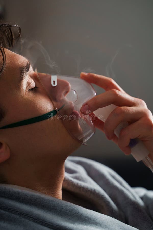 Using compressor nebulizer for disease treatment at home. Man inhaling through oxygen mask for cough treatment. stock photo
