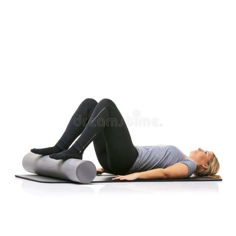 Using a Foamroller To Raise Her Legs. a Young Woman Lying on an Exercise Mat with Her Feet on a