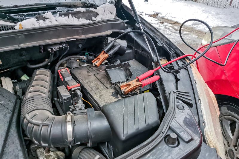 Using jumper cables to charge dead car battery during the winter season