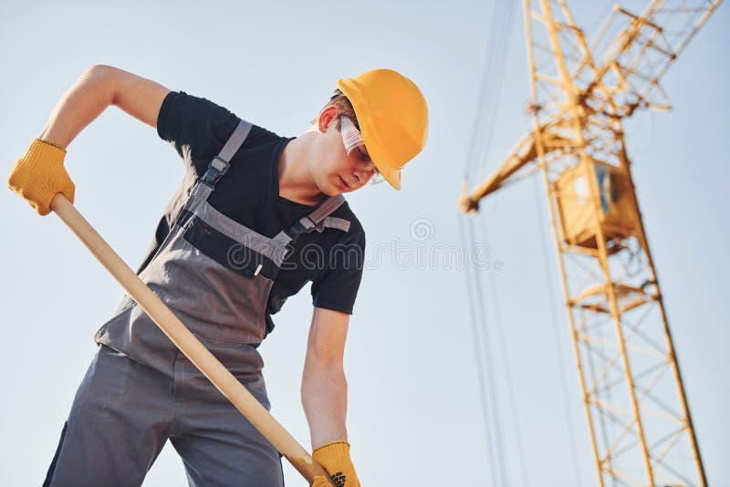 Using Showel. Construction Worker in Uniform and Safety Equipment Have