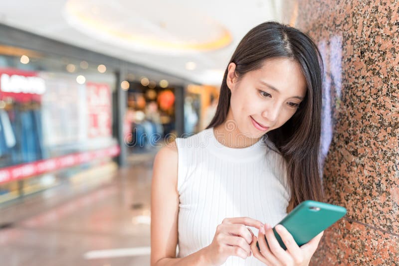 Uso della giovane donna del telefono cellulare nel centro commerciale fotografie stock libere da diritti Uso della giovane donna del telefono cellulare nel centro commerciale fotografie stock libere da diritti
