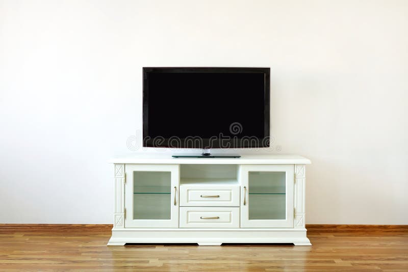 Large widescreen TV set on the white dresser in a bright room. Large widescreen TV set on the white dresser in a bright room.