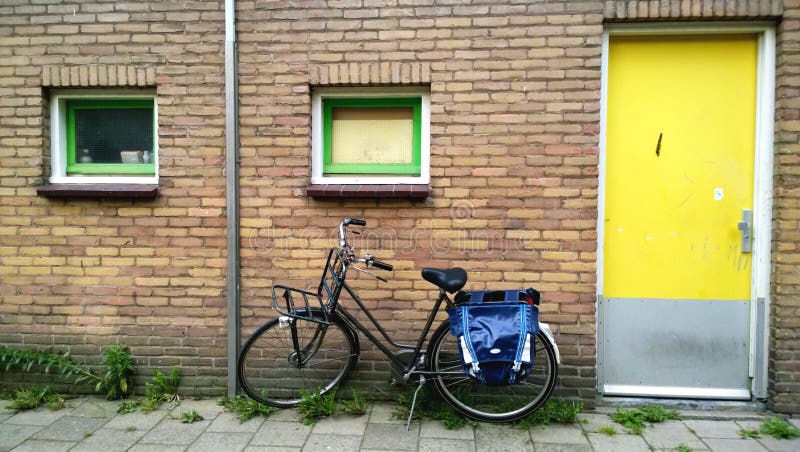 The usual Amsterdam entrance in a residential house, near a parked bike. Bright yellow front door stock photography The usual Amsterdam entrance in a residential house, near a parked bike. Bright yellow front door stock photography