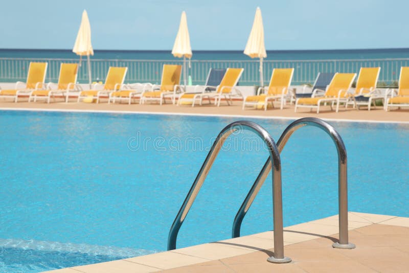 Uswimming pool with stair, lounges and umbrellas stock photos