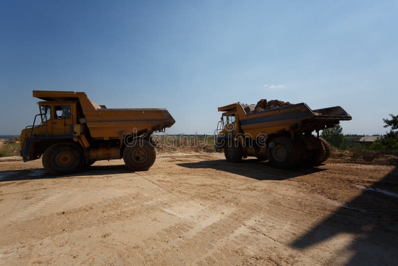 Tipper or dumper trucks, dump trucks in a sand quarry, transporting of sand, gravel, demolition waste on a natural background. Tipper or dumper trucks, dump trucks in a sand quarry, transporting of sand, gravel, demolition waste on a natural background.