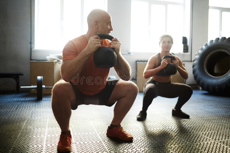 Strong men and women exercising with kettlebell in gym. Strong men and women exercising with kettlebell in gym