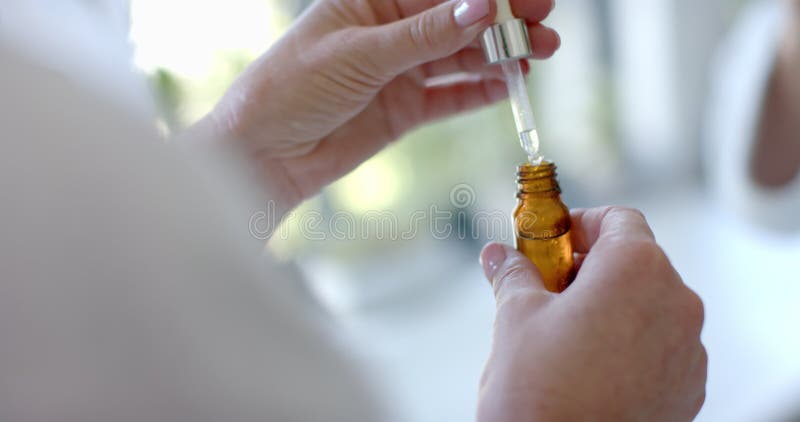 Utilisation de dropper pour ajouter du liquide dans une bouteille femme mature préparant des huiles essentielles banque de vidéos