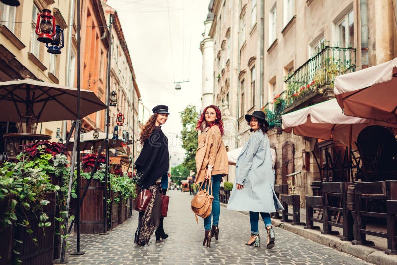 Utomhus- skott av tre unga kvinnor som går på stadsgatan Flickor som vänder och ser kameran royaltyfria bilder Utomhus- skott av tre unga kvinnor som går på stadsgatan Flickor som vänder och ser kameran royaltyfria bilder