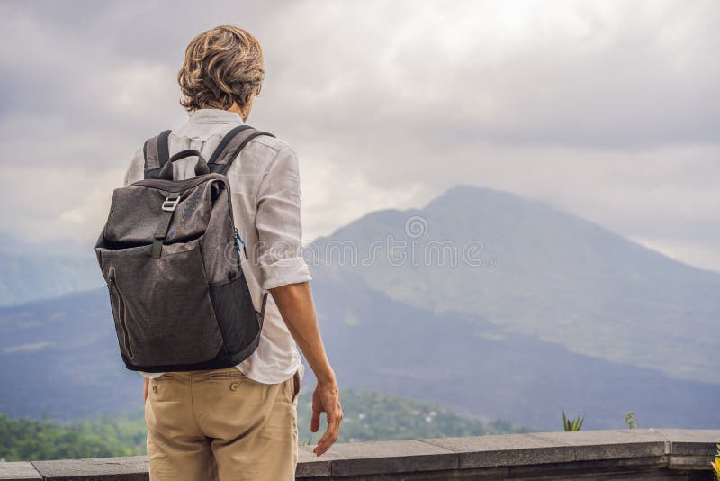 Utomhus- stående av den unga mannen som ser på Batur vulkan- och Agung bergsikt på morgonen från Kintamani, Bali royaltyfri fotografi Utomhus- stående av den unga mannen som ser på Batur vulkan- och Agung bergsikt på morgonen från Kintamani, Bali royaltyfri fotografi