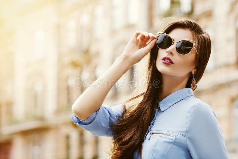 Utomhus- stående av en ung härlig säker kvinna som poserar på gatan Modell som bär stilfull solglasögon flicka